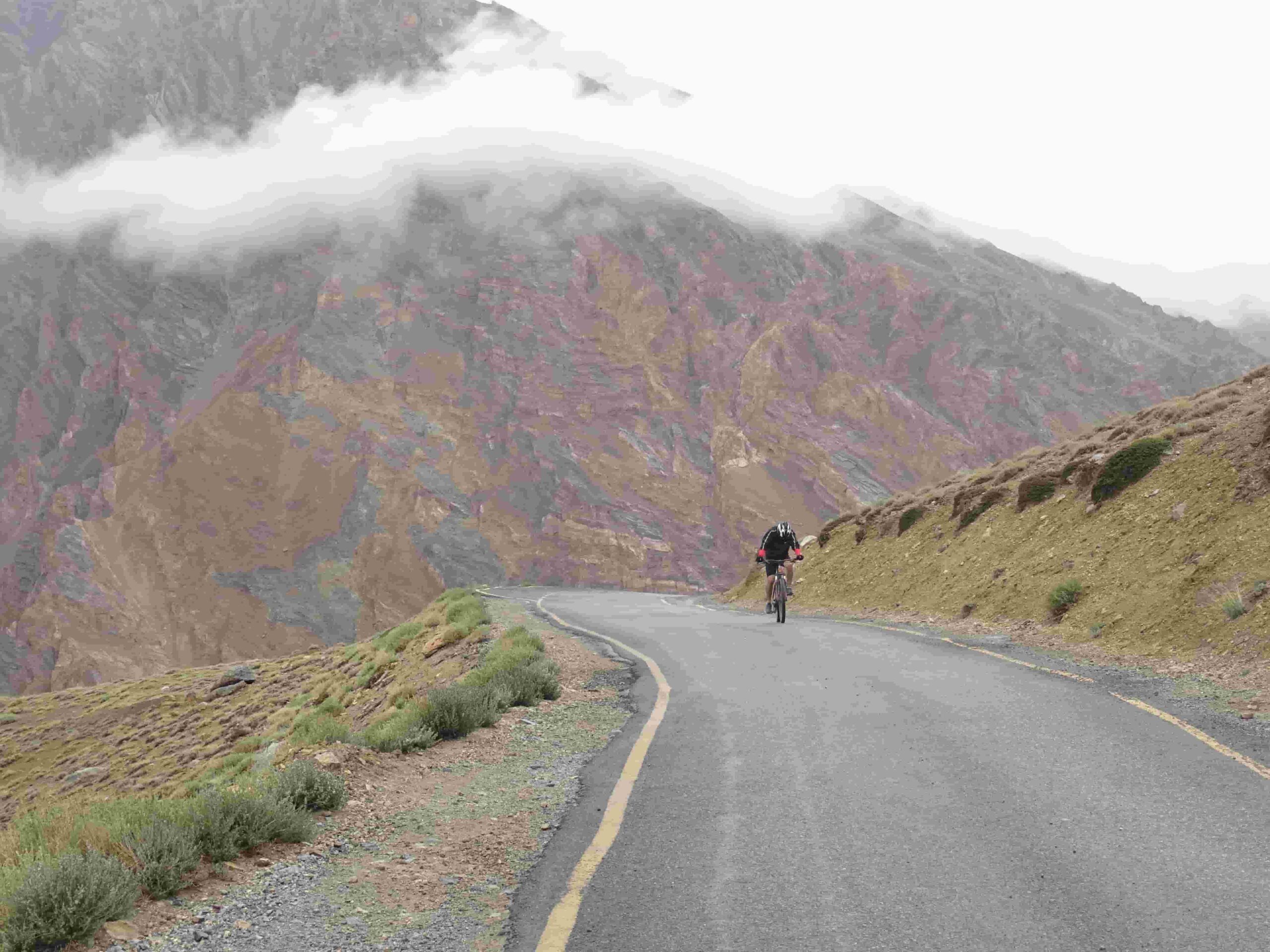 Cyclist climbing a switchback road in the Indian Himalayas on a Manali to Leh cycling tour