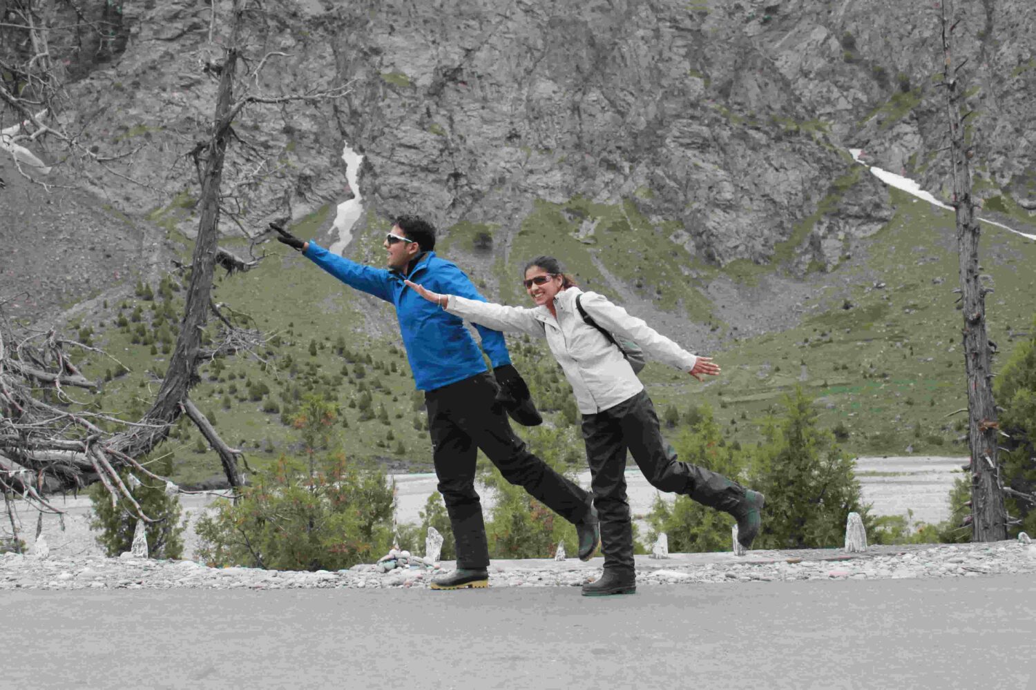 A happy couple posing playfully beside a mountain road during Into Wild Himalaya’s Foothills of the Himalayas Motorcycle Tour, showing the joy and freedom of riding through the Himalayas.