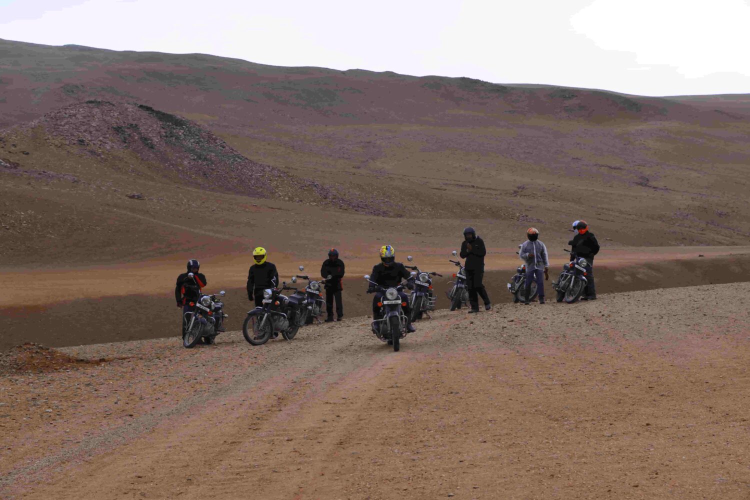 Bikers riding Royal Enfield motorcycles across Thar Desert dunes in Rajasthan