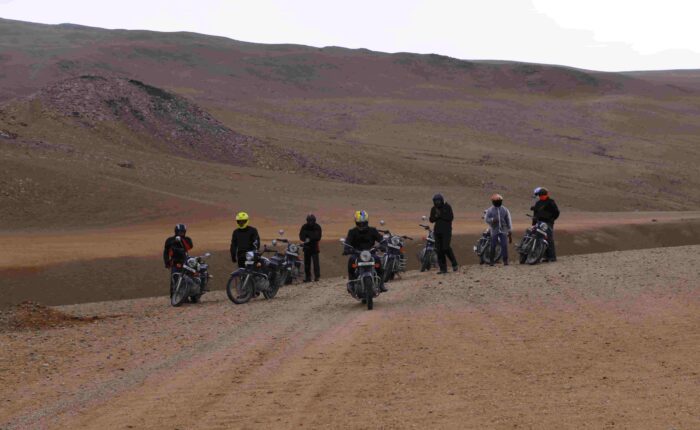 Bikers riding Royal Enfield motorcycles across Thar Desert dunes in Rajasthan