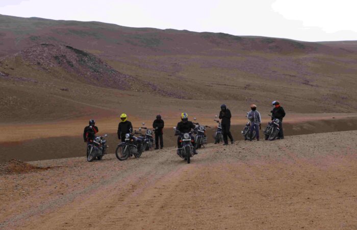 Bikers riding Royal Enfield motorcycles across Thar Desert dunes in Rajasthan