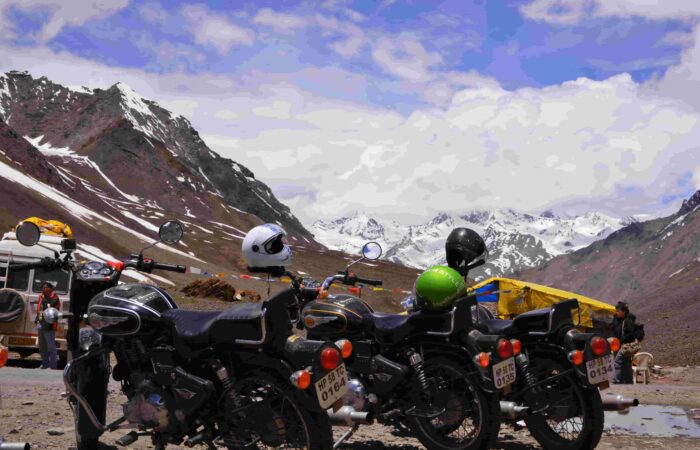 Motorcycles parked with helmets on mirrors as bikers admire snow-covered Himalayan mountains on the Manali to Leh route