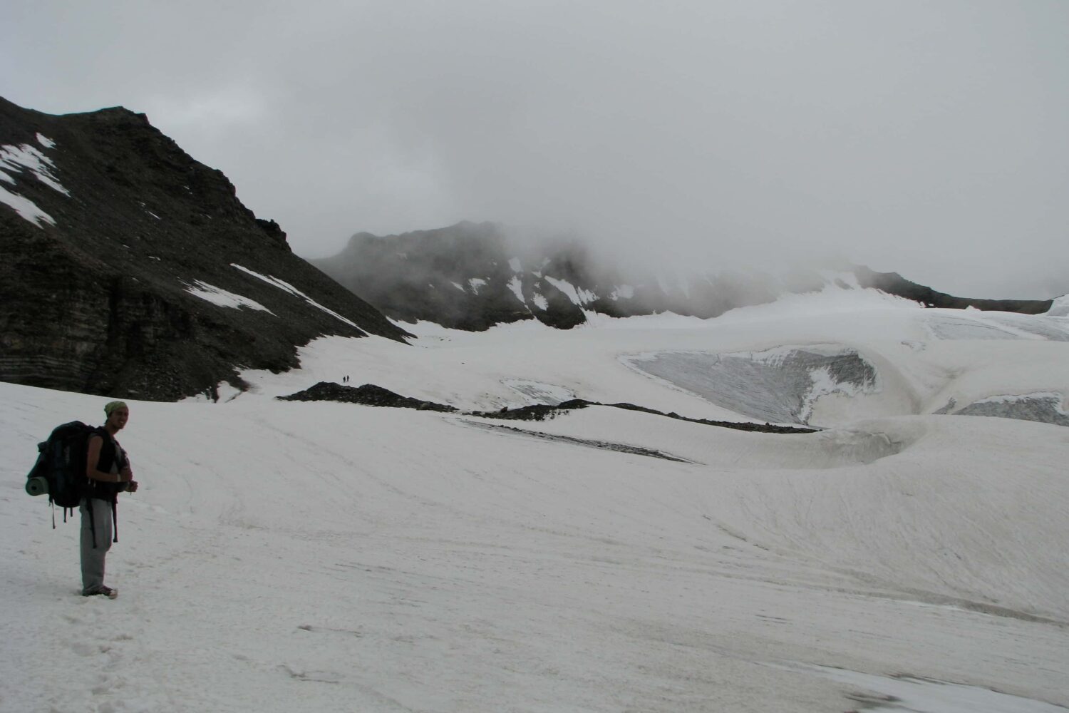 Trekker walking across a snowy glacier during the Pin Parvati Pass Trek in the Himalayas.