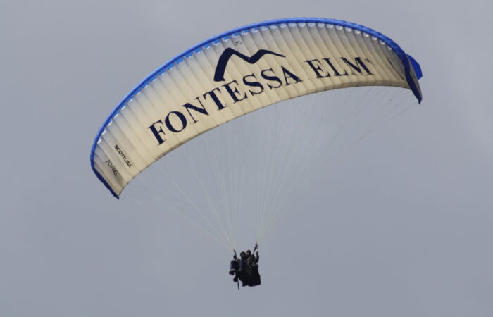 Instructor teaching beginner students basic paragliding control techniques on the training slope in Manali, Himachal Pradesh.