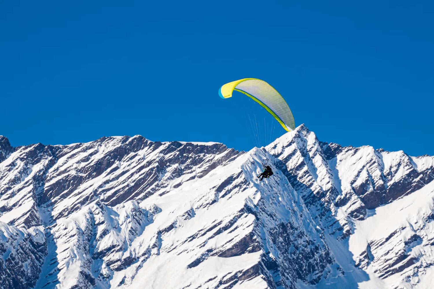 Instructor guiding a beginner pilot mid-flight during basic paragliding course in Manali, Himachal Pradesh.