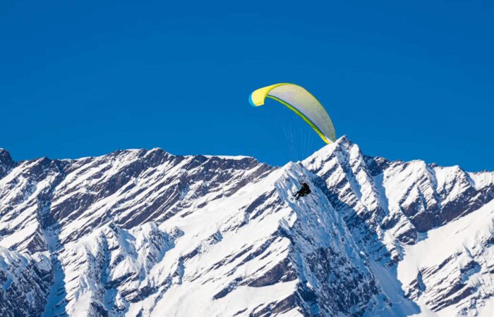 Instructor guiding a beginner pilot mid-flight during basic paragliding course in Manali, Himachal Pradesh.