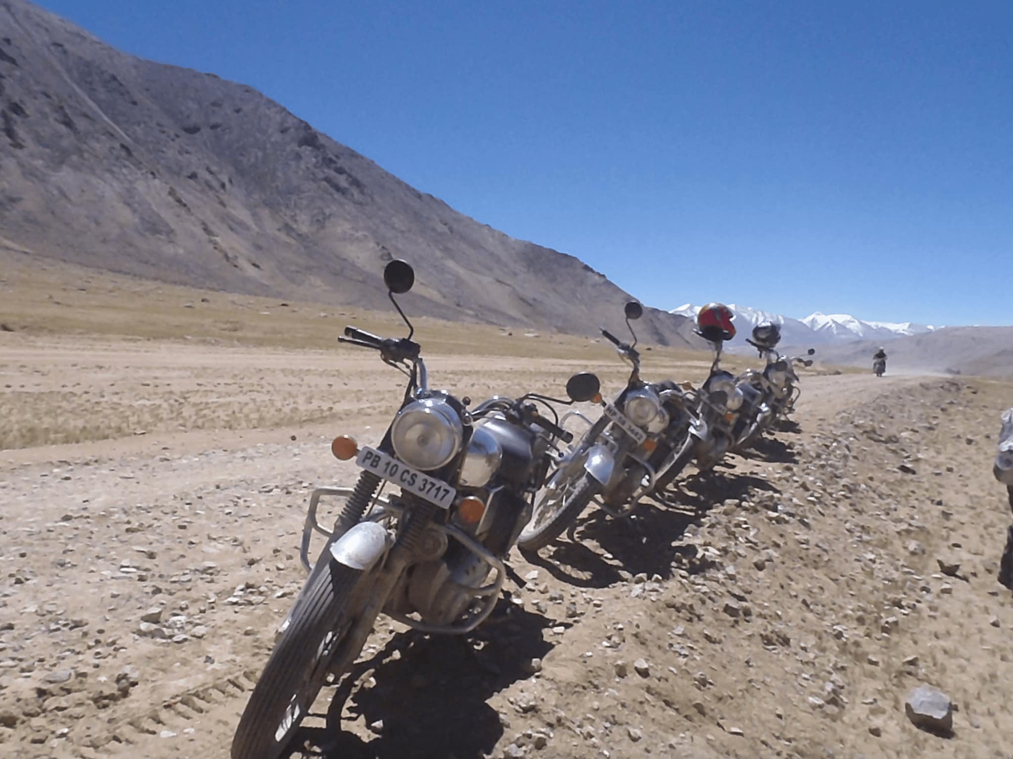 Royal Enfield motorcycles parked on a dirt road in the Himalayas during a motorcycle expedition on the Manali Leh Highway.