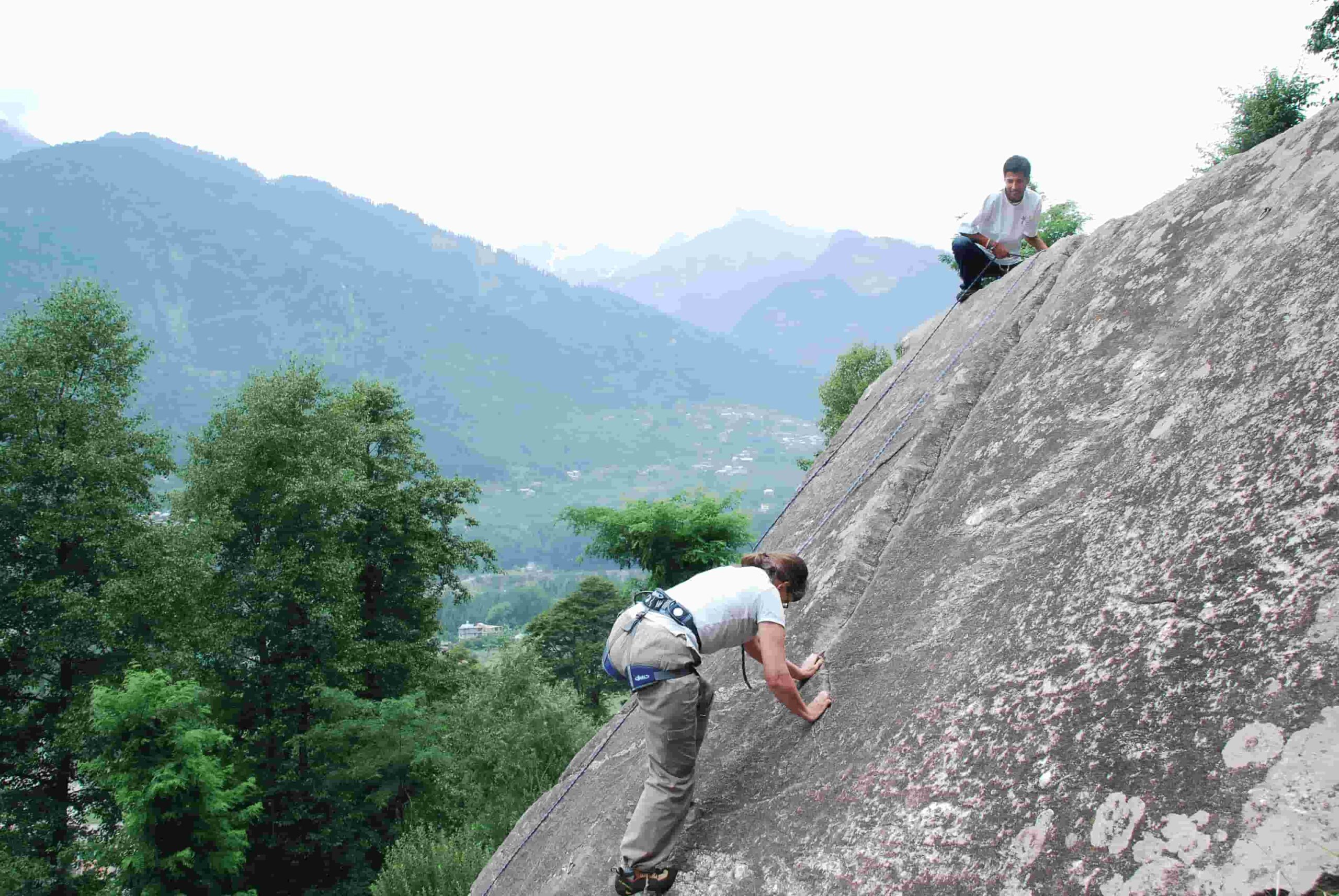 Climber scaling granite slab during lead climbing session in Aleo, Manali with Into Wild Himalaya instructors.