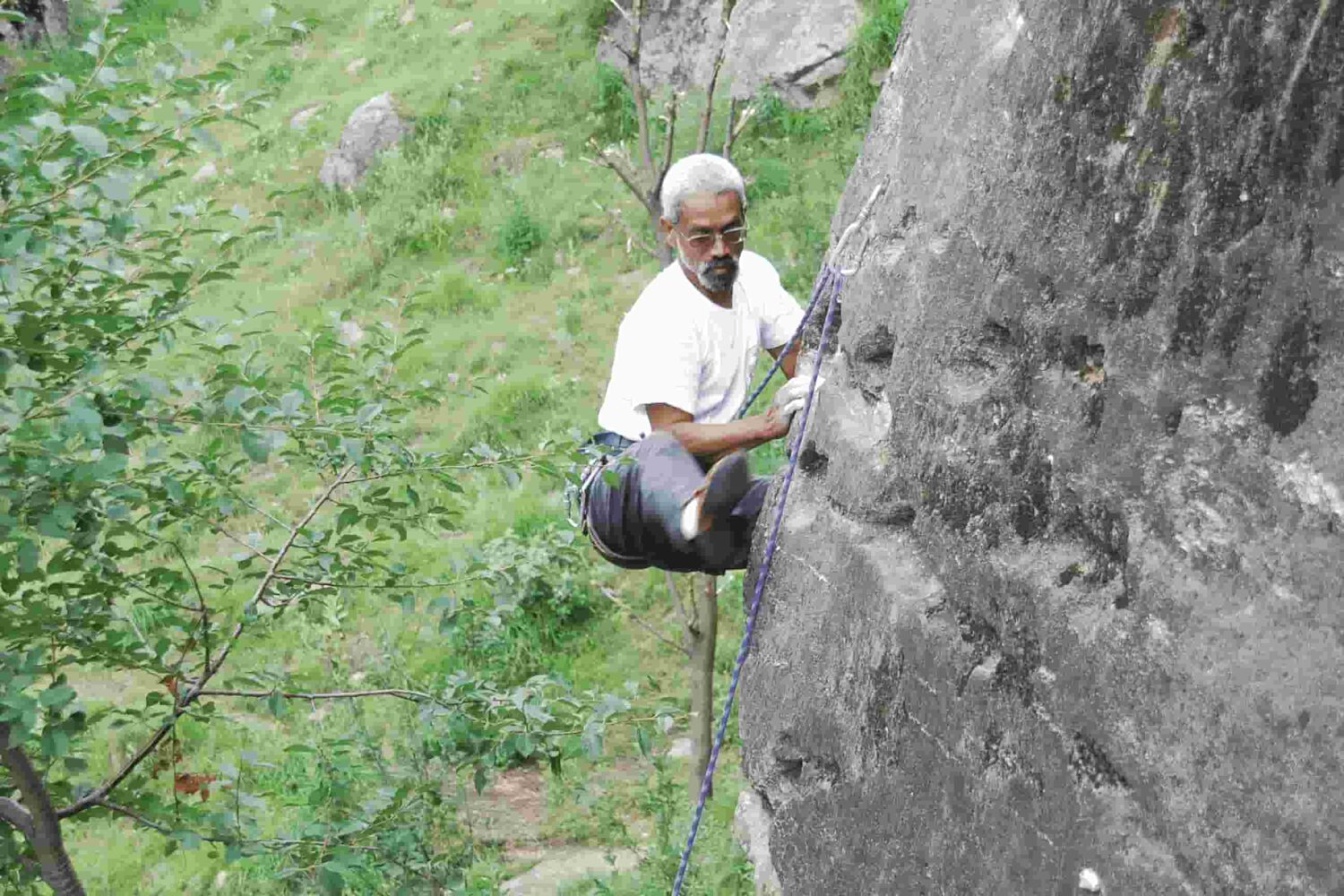 Climber scaling steep granite wall during lead climbing session in Aleo, Manali with Into Wild Himalaya.