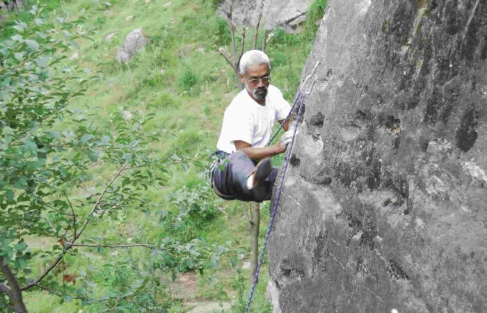Climber scaling steep granite wall during lead climbing session in Aleo, Manali with Into Wild Himalaya.