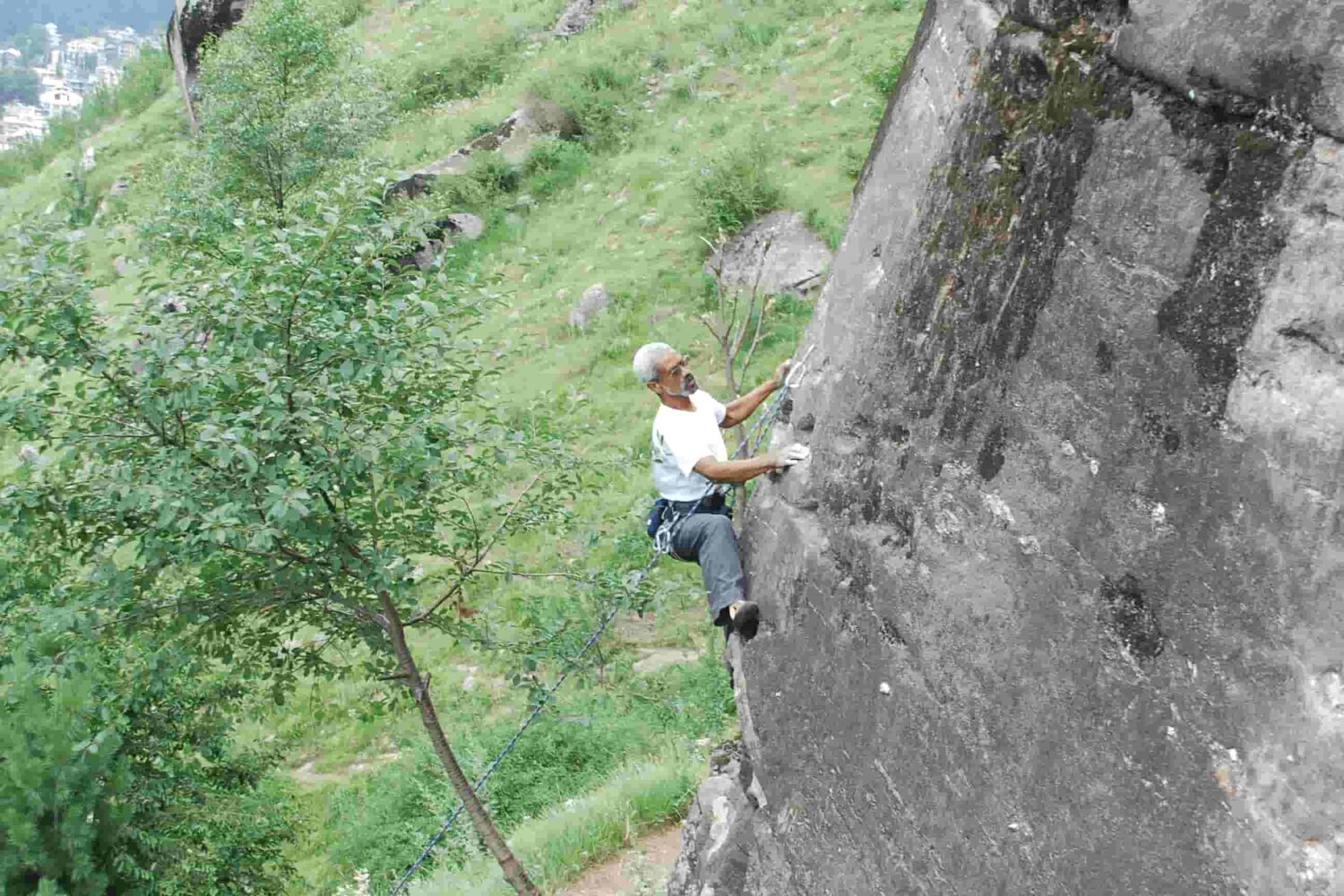 Climber scaling granite wall during guided rock climbing session in Aleo, Manali organized by Into Wild Himalaya.