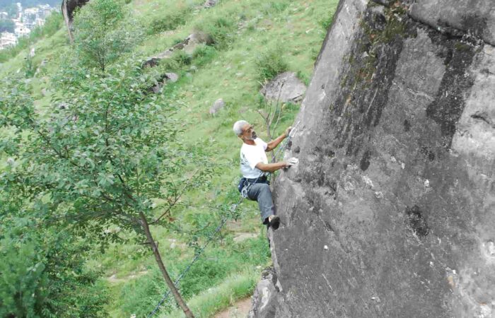 Climber scaling granite wall during guided rock climbing session in Aleo, Manali organized by Into Wild Himalaya.