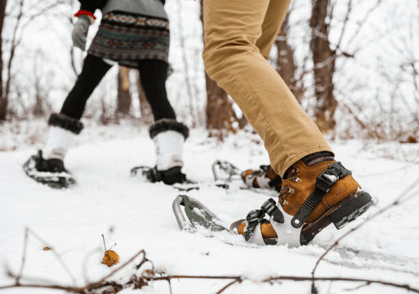 Close-up of a couple’s legs snowshoeing through a snow-covered cedar forest in Manali, Himachal Pradesh