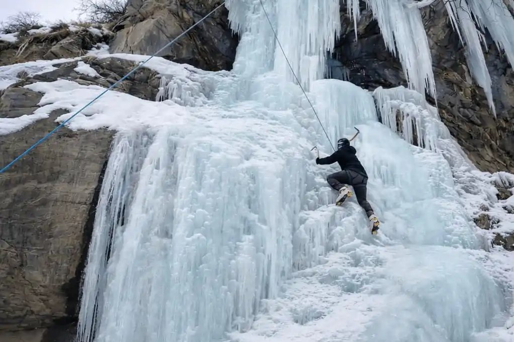 A roped ice climber working up a frozen waterfall on a guided climb in the Indian Himalayas