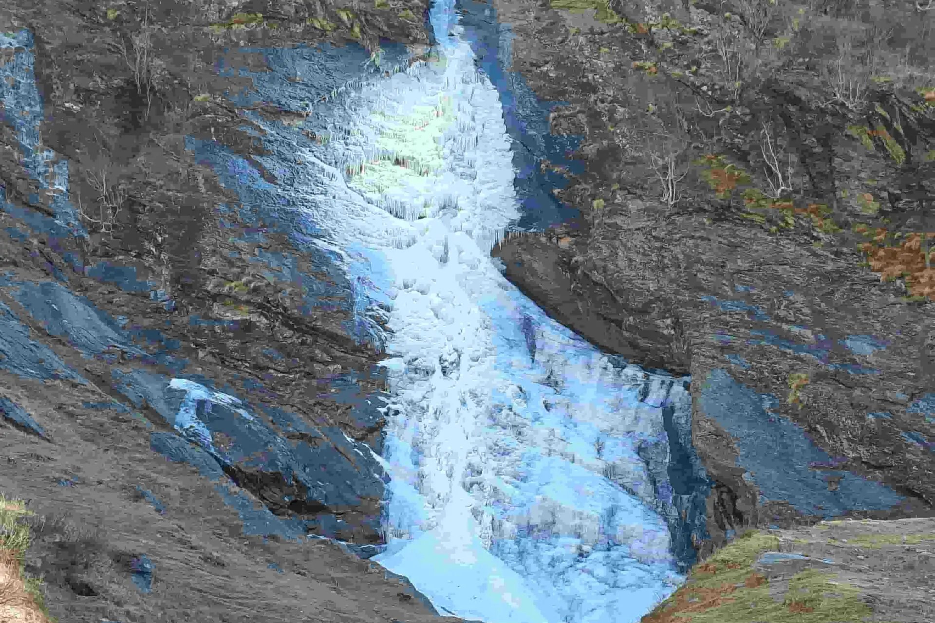 A frozen blue waterfall running down a rock gully in the Indian Himalayas